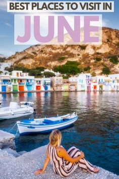 a woman sitting on the edge of a pier next to boats