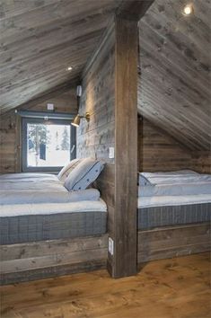 an attic bedroom with wooden walls and flooring, two beds are in the corner