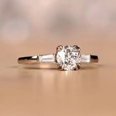 an engagement ring with three baguets on the side and a diamond in the middle