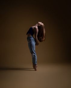 a woman standing on one leg with her head in the air and hands behind her back