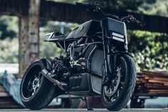 a black motorcycle parked in front of a wooden structure