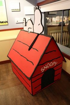 there is a cardboard dog house with snoopy on the roof