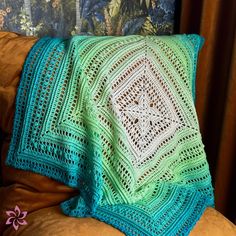 a green crocheted blanket sitting on top of a couch