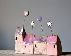 three little pink houses with stars on them sitting on top of a wooden table in front of a gray wall