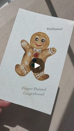 a person holding up a card with a ginger - painted gingerbread on it's front