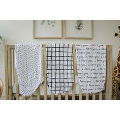 three baby swaddles hanging from a crib with giraffes in the background