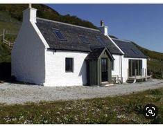 a small white house sitting on the side of a hill