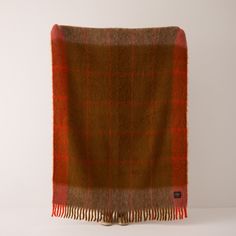 an orange and brown plaid blanket on a white background