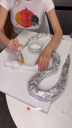 a woman sitting at a table with some silver decorations on it and a white cup