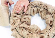 a person is holding a pair of scissors near a burlap wreath