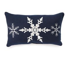 a blue pillow with white snowflakes on the front and back, sitting on a white background