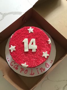 a red and white birthday cake with the number fourteen on it in a cardboard box