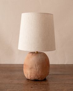 a table lamp sitting on top of a wooden table next to a white lampshade