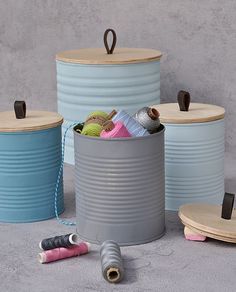 three buckets with yarn and thread on the floor next to each other in front of a cement wall