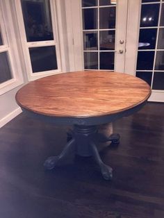 a wooden table sitting on top of a hard wood floor next to two white doors