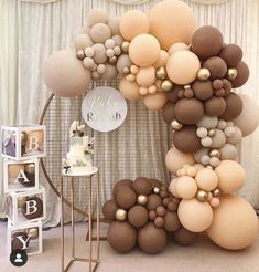 a large balloon arch with gold and white balloons on it, next to a cake