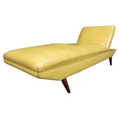 a yellow leather chaise lounger with wooden legs and feet rests against a white background