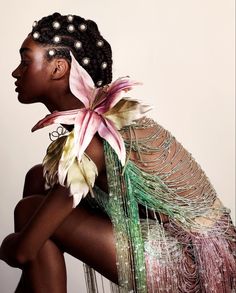 a woman with flowers in her hair sitting on the ground