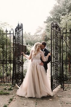 a bride and groom standing in front of an iron gate