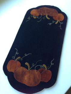 a black rug with pumpkins and vines on the bottom is sitting on a table