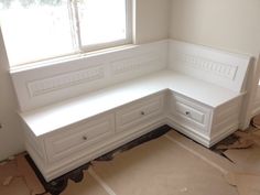 a corner bench in the middle of a room with white walls and trim around it