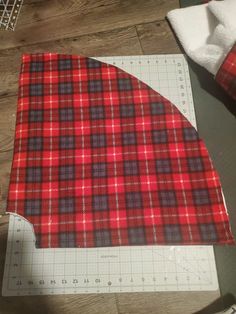 a red and black plaid fabric on a cutting board next to a pair of scissors