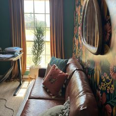 a brown leather couch sitting in front of a window