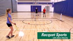 three people are playing badminton in an indoor gym