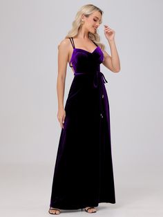 a woman wearing a purple velvet dress with straps on the waist and side, standing in front of a white background