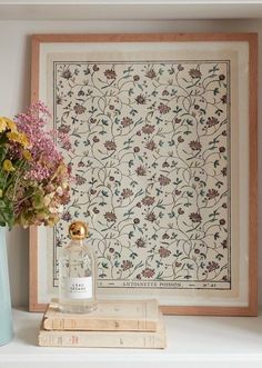 a vase filled with flowers sitting on top of a white shelf next to a painting