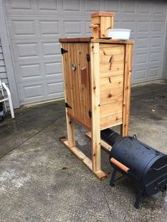 a large wooden birdhouse sitting next to a black barrel on top of a cement floor