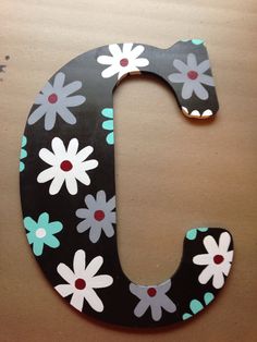 the letter j is decorated with flowers and has black, white, and blue paint