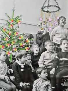 a group of children sitting next to each other in front of a small christmas tree