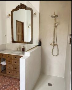 a bathroom with a sink, mirror and shower head in the corner next to a tiled floor