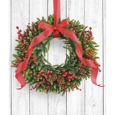 a christmas wreath hanging on the side of a wooden wall with red ribbon and pine cones