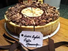 a cake with chocolate and banana slices on it sitting on a table next to a ribbon