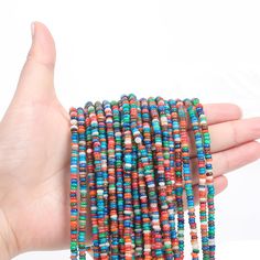 a hand is holding several multicolored beads