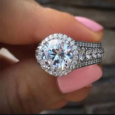 a woman's hand holding an engagement ring with diamonds on it and a pink manicure