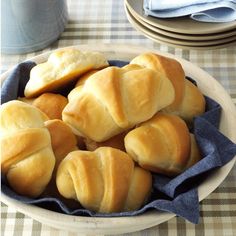 a white bowl filled with croissants on top of a checkered table cloth