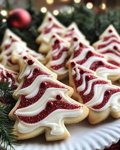 christmas cookies decorated with white icing and red glazes on a paper plate