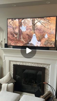 a flat screen tv mounted above a fireplace in a living room with ghost decorations on the mantle