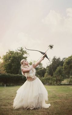 a woman in a white dress holding a bow and arrow