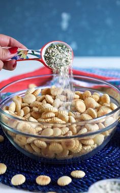 a person is pouring peanuts into a glass bowl on a blue place mat with red and white polka dots