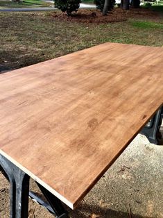 a wooden table sitting on top of a metal frame in the middle of a park