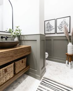 a bathroom with gray walls and white flooring, two framed pictures on the wall