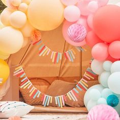 balloons and streamers are arranged in front of a teepee tent for a birthday party