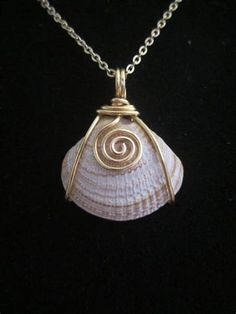 a shell with a spiral design on it sitting on a black surface in front of a chain