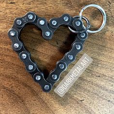 a heart shaped keychain on top of a wooden table with a metal chain attached to it