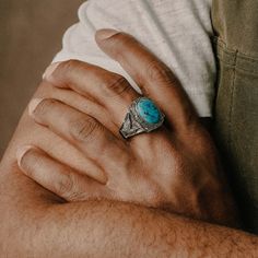 a man wearing a ring with a turquoise stone in it's middle and his arm wrapped around him