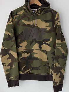 Nike SpellOut Logo Camo Green Pullover Hoodie Blue Tag 639978-010 Mens Small. Minor wear/gold on the N on the front. Nice sweatshirt. Weighs: 1lb 2.4oz Measurements, laying flat: Pit to pit: 20.5” Front length, collar to bottom: 23” Back length, collar to bottom: 25.5” Sleeve length from pit: 21.5” Hood, front, top to collar: 14” This item is used. This item has been washed using arm&hammer detergent. Since not all items are originally ours from new, throughout the life of this item, it may have American Flag Hoodie, Camouflage Hoodie, Green Pullover, Camo Hoodie, Hoodie Green, Jackets Men Fashion, Fun Sweatshirts, Men Fashion, Army Green